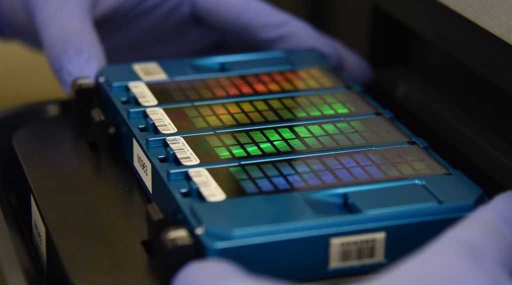 In this picture taken on August 22, 2018, a technician places an array containing DNA information in a scanner at GeseDNA Technology in Beijing. - China's DNA sequencing market was worth about 7.2 billion yuan (1.05 billion USD) last year and is forecast to grow to 18.3 billion yuan in 2022, according to estimates by Beijing-based CCID Consulting. (Photo by GREG BAKER / AFP) / To go with China-genetics-demographics-DNA, Feature by Danni Zhu and Elizabeth Law