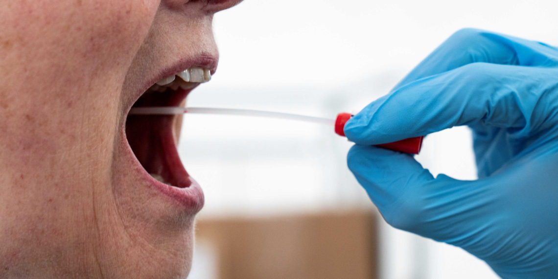 A medical worker performs a mouth swab on a patient to test for the coronavirus disease (COVID-19) in a new tent extension of Danish National Hospital Rigshospitalet in Copenhagen, Denmark April 2, 2020.  Ritzau Scanpix/Niels Christian Vilmann via REUTERS    ATTENTION EDITORS - THIS IMAGE WAS PROVIDED BY A THIRD PARTY. DENMARK OUT. NO COMMERCIAL OR EDITORIAL SALES IN DENMARK.