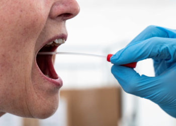 A medical worker performs a mouth swab on a patient to test for the coronavirus disease (COVID-19) in a new tent extension of Danish National Hospital Rigshospitalet in Copenhagen, Denmark April 2, 2020.  Ritzau Scanpix/Niels Christian Vilmann via REUTERS    ATTENTION EDITORS - THIS IMAGE WAS PROVIDED BY A THIRD PARTY. DENMARK OUT. NO COMMERCIAL OR EDITORIAL SALES IN DENMARK.