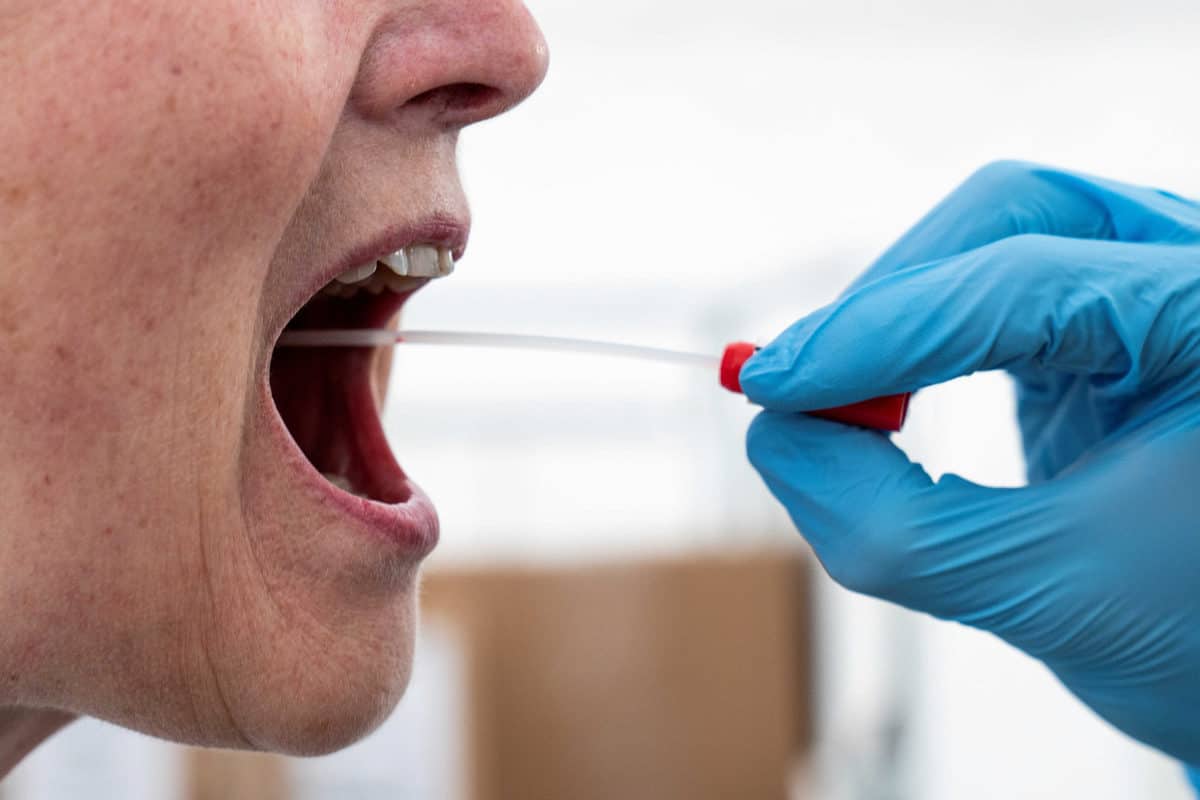 A medical worker performs a mouth swab on a patient to test for the coronavirus disease (COVID-19) in a new tent extension of Danish National Hospital Rigshospitalet in Copenhagen, Denmark April 2, 2020.  Ritzau Scanpix/Niels Christian Vilmann via REUTERS    ATTENTION EDITORS - THIS IMAGE WAS PROVIDED BY A THIRD PARTY. DENMARK OUT. NO COMMERCIAL OR EDITORIAL SALES IN DENMARK.