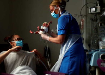 Neonatal Nurse Kirsty Hartley carries premature baby Theo Anderson to his mother Kirsty Anderson in the Neonatal Intensive Care Unit at the Lancashire Women and Newborn Centre at Burnley General Hospital during the coronavirus disease (COVID-19) outbreak, in East Lancashire, Burnley, Britain, May 15, 2020. REUTERS/Hannah McKay/Pool/File Photo     TPX IMAGES OF THE DAY     SEARCH "GLOBAL COVID-19" FOR THIS STORY. SEARCH "WIDER IMAGE" FOR ALL STORIES