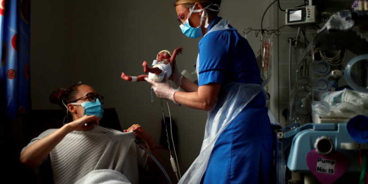Neonatal Nurse Kirsty Hartley carries premature baby Theo Anderson to his mother Kirsty Anderson in the Neonatal Intensive Care Unit at the Lancashire Women and Newborn Centre at Burnley General Hospital during the coronavirus disease (COVID-19) outbreak, in East Lancashire, Burnley, Britain, May 15, 2020. REUTERS/Hannah McKay/Pool/File Photo     TPX IMAGES OF THE DAY     SEARCH "GLOBAL COVID-19" FOR THIS STORY. SEARCH "WIDER IMAGE" FOR ALL STORIES