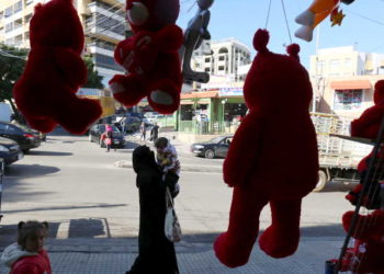 A woman holds her child as she walks past teddy bears for sale ahead of Valentine's Day in Beirut's southern suburbs, Lebanon February 12, 2016. REUTERS/Aziz Taher