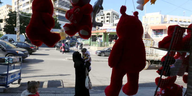 A woman holds her child as she walks past teddy bears for sale ahead of Valentine's Day in Beirut's southern suburbs, Lebanon February 12, 2016. REUTERS/Aziz Taher