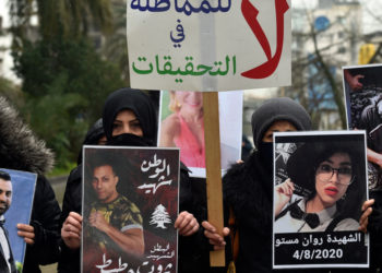 epa09023654 Families and relatives of victims of the 04 August Beirut port explosion carry pictures and a placard with Arabic words which reads, 'No to stalling the investigation' to protest the step down of a judge Fadi Sawan appointed to investigate the explosion in the Beirut port in front of the Justice Palace in Beirut, Lebanon, 19 February 2021. A highest court in Lebanon asked the judge appointed to investigate the explosion in the Beirut port on 04 August 2020 to step down.  EPA-EFE/WAEL HAMZEH