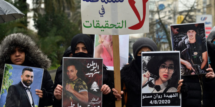 epa09023654 Families and relatives of victims of the 04 August Beirut port explosion carry pictures and a placard with Arabic words which reads, 'No to stalling the investigation' to protest the step down of a judge Fadi Sawan appointed to investigate the explosion in the Beirut port in front of the Justice Palace in Beirut, Lebanon, 19 February 2021. A highest court in Lebanon asked the judge appointed to investigate the explosion in the Beirut port on 04 August 2020 to step down. EPA-EFE/WAEL HAMZEH
