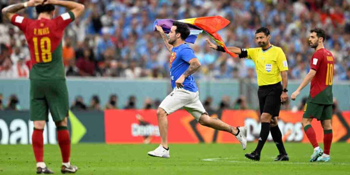 A man wearing a t-shirt reading "Save Ukraine" and "Respect For Iranian Woman" runs on the pitch waving a rainbow flag on the pitch during the Qatar 2022 World Cup Group H football match between Portugal and Uruguay at the Lusail Stadium in Lusail, north of Doha on November 28, 2022. (Photo by PATRICIA DE MELO MOREIRA / AFP)