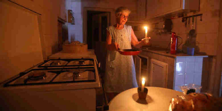 A woman holds a lighted candle after power cuts at her house in Beirut, Lebanon.