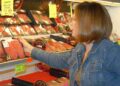 B0DDTX A woman selects meat while grocery shopping.. Image shot 2008. Exact date unknown.